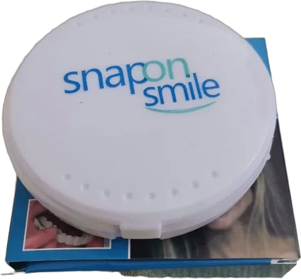 SnapOnSmile — okrągłe białe etui z logo marki, postawione na niebieskim pudełku zdejmowanych nakładek na zęby